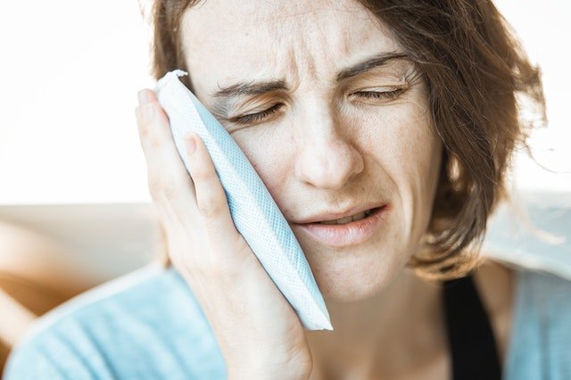 Donna con un impacco sulla guancia, a causa del mal di denti