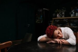 Donna che dorme con braccia e testa appoggiate su un tavolo